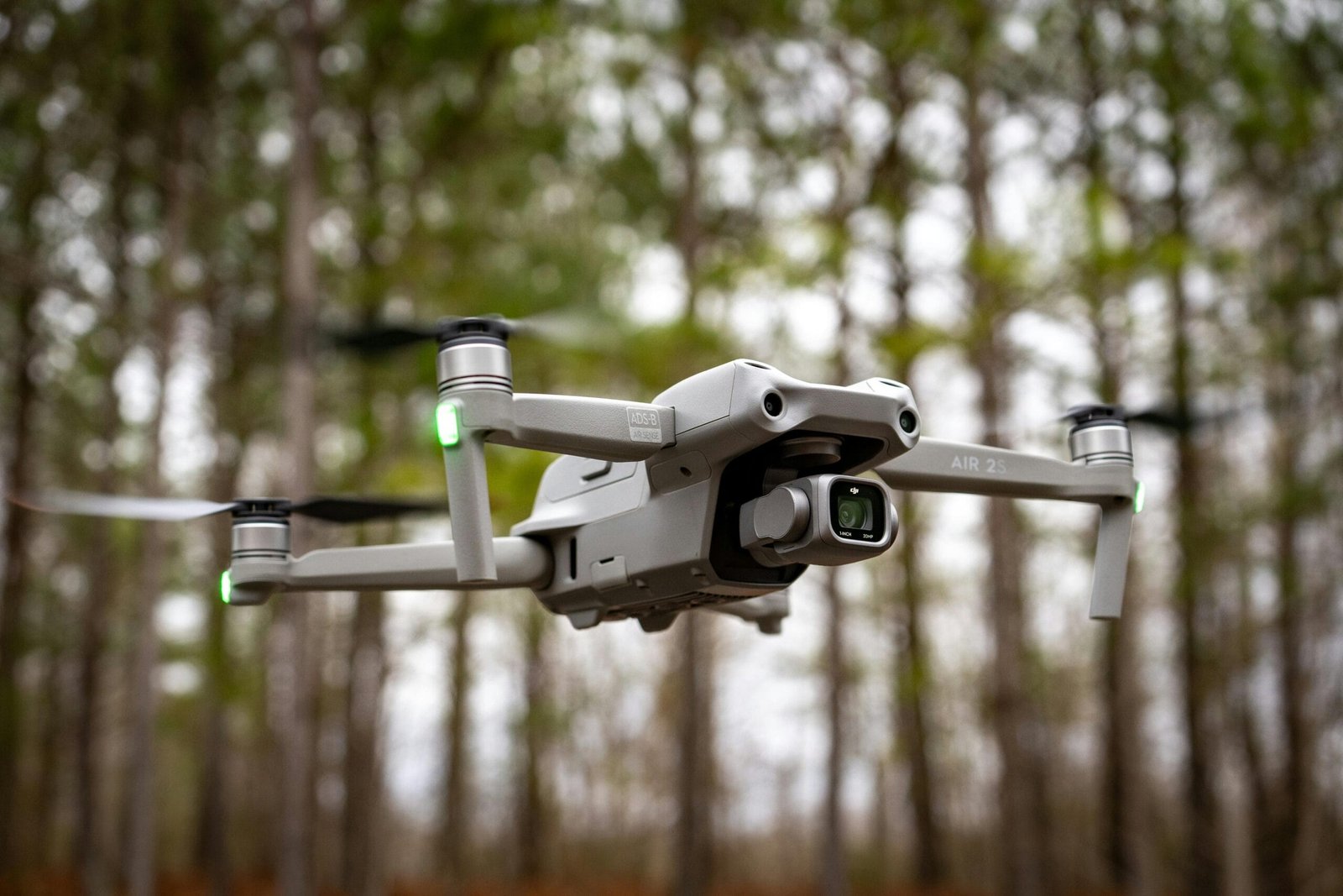 "Content Creation" Close-up of a drone in midair with trees in the background, showcasing technology and nature.