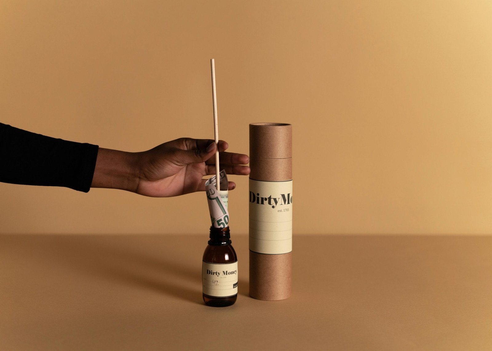 "Content Creation" A hand holding a stick with money wrapped around it inside a labeled bottle against a beige backdrop.